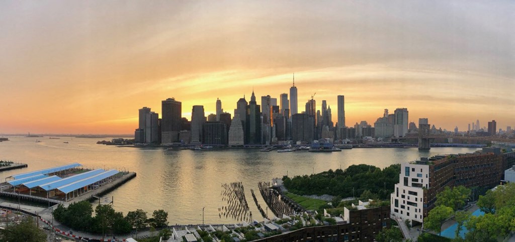 a view of the city skyline at sunset with the river in the foreground
